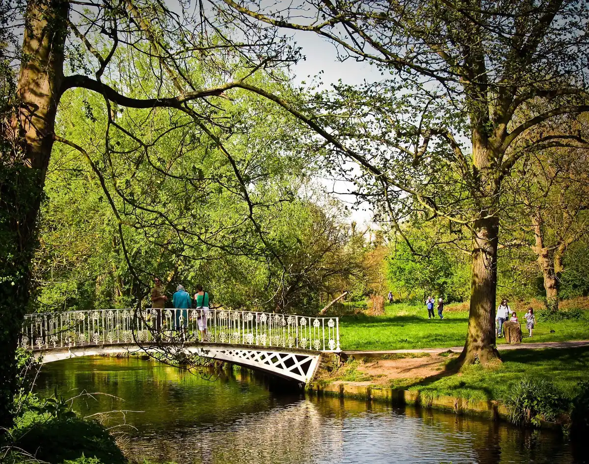 A white footbridge over the River Wandle in Morden Hall Park